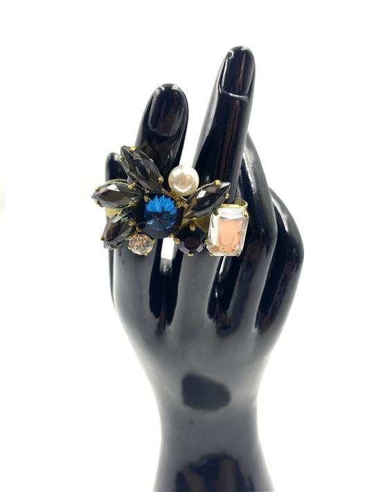 Multicolor rhinestone double finger adjustable ring with black, blue, pink, and clear gems, and a pearl, on a gold-tone band.