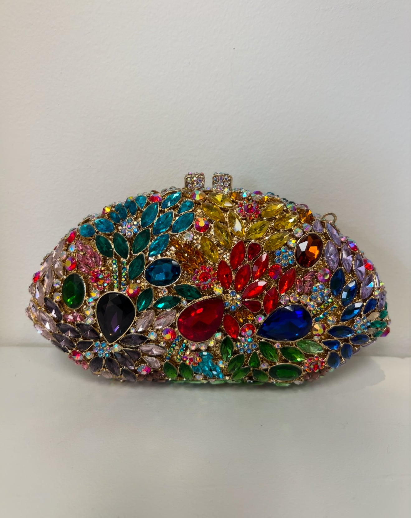 Oval clutch covered in vibrant, multicolored rhinestones and large faceted jewels on a gold-tone metal frame.