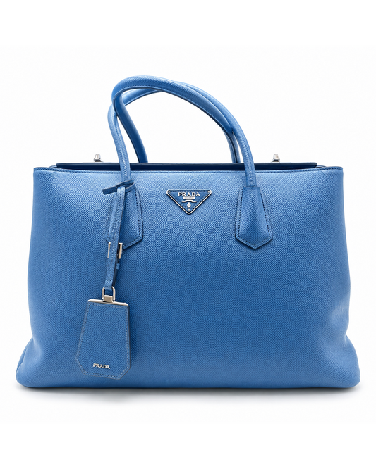 Prada blue Saffiano leather large Twin tote with silver hardware, top handles, and a signature metal triangle logo.