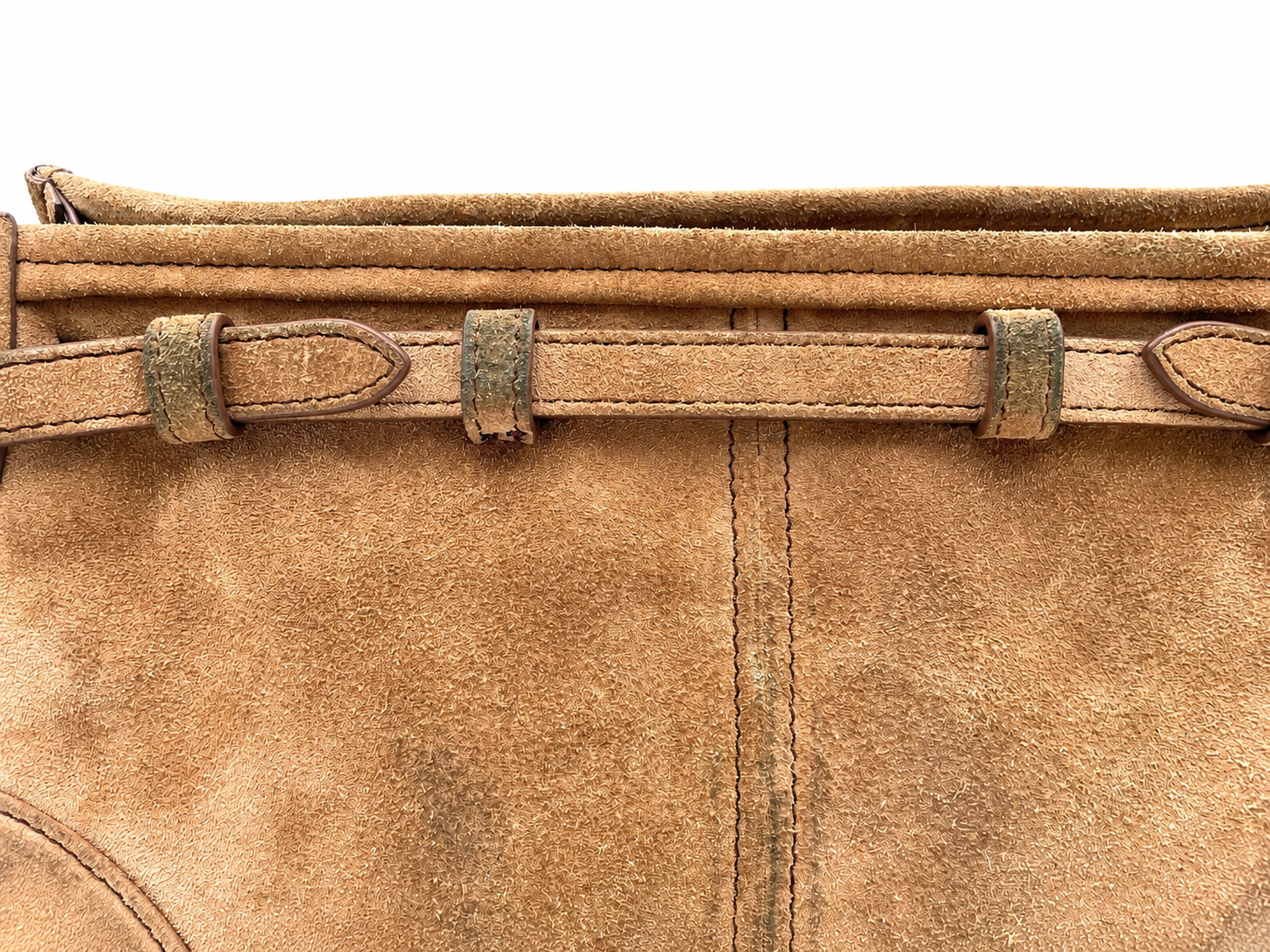 Close-up of a cinnamon brown Prada Bonnie suede shoulder bag featuring a decorative horizontal strap and visible texture.