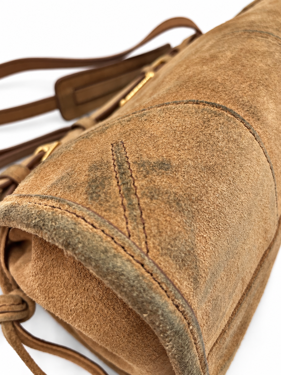 Close-up of a cinnamon brown suede Prada Bonnie shoulder bag showing visible color transfer and gold hardware details.