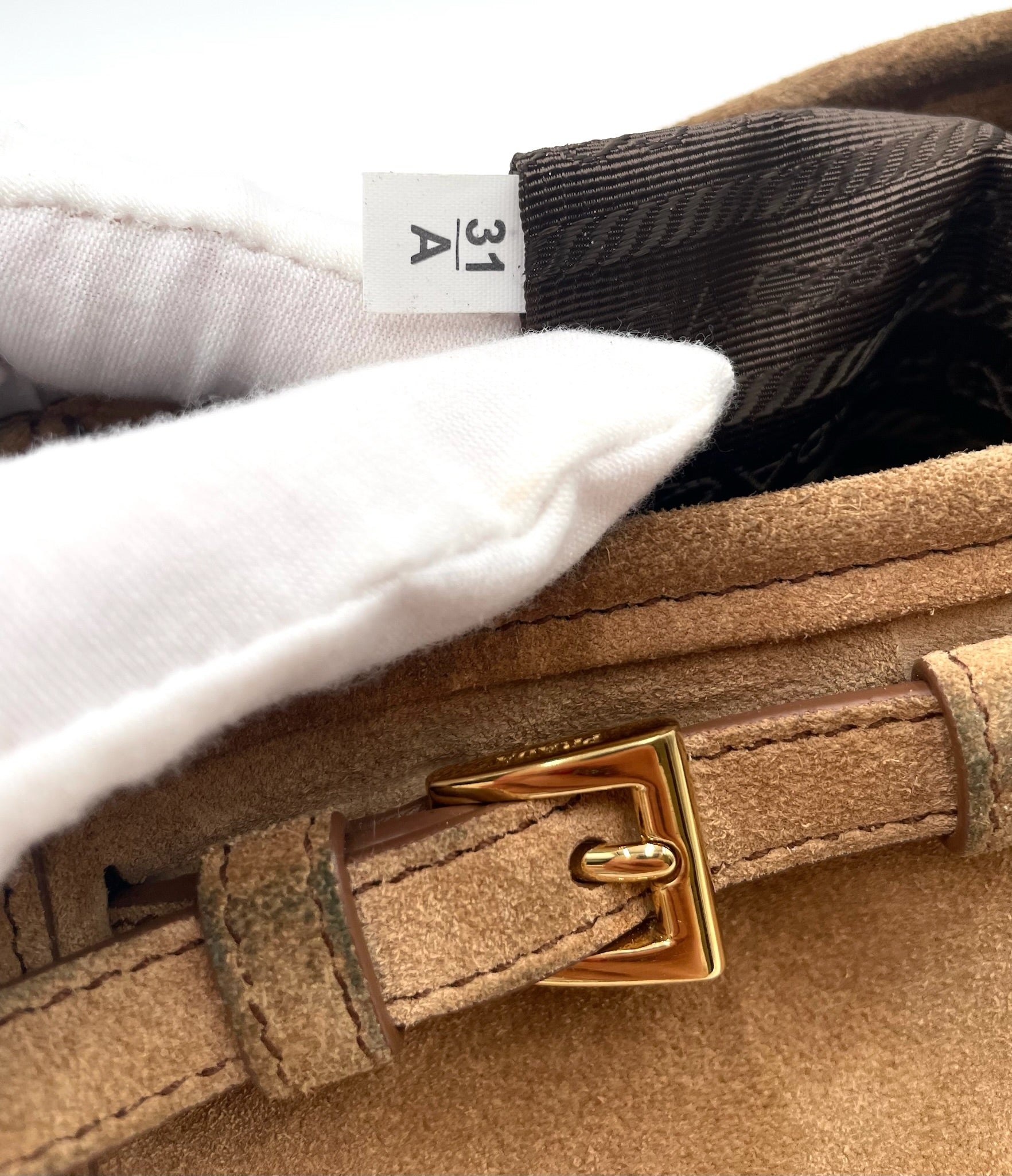 Cinnamon brown suede Prada Bonnie bag featuring a gold buckle, logo jacquard lining, and an interior factory tag numbered 31 A.