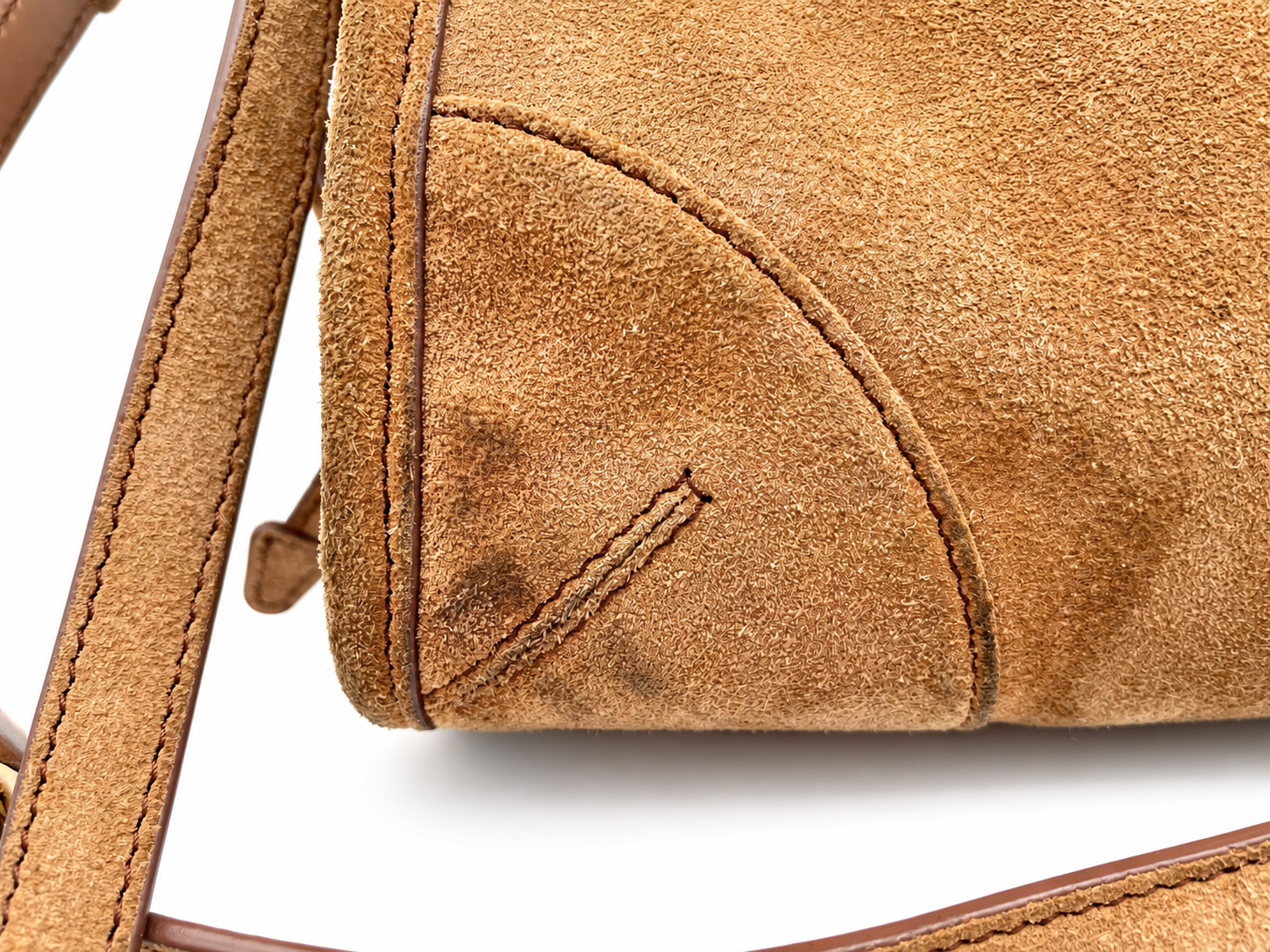 Close-up of a cinnamon brown suede Prada Bonnie shoulder bag showing stitching detail and leather strap.