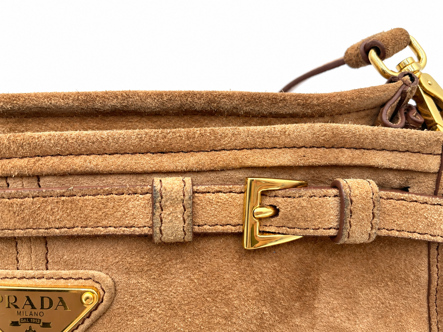 Cinnamon brown suede Prada Bonnie shoulder bag featuring gold hardware, a buckled strap detail, and a triangular logo plaque.