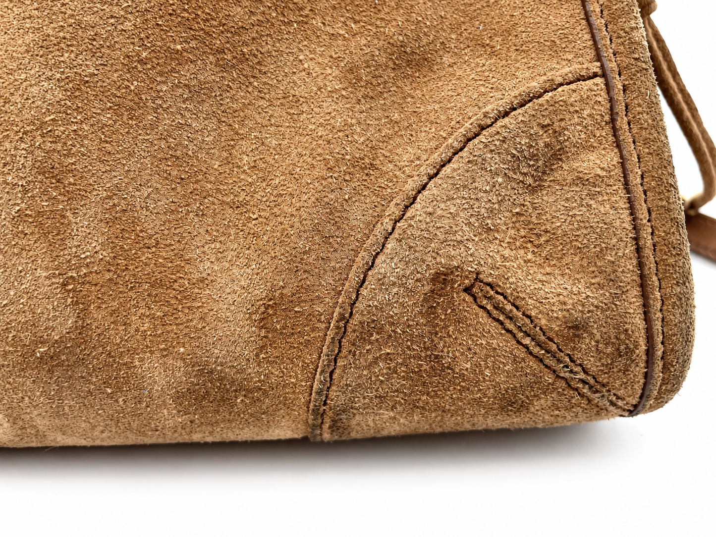 Close-up of a cinnamon brown Prada Bonnie suede shoulder bag showing textured material and reinforced corner stitching.