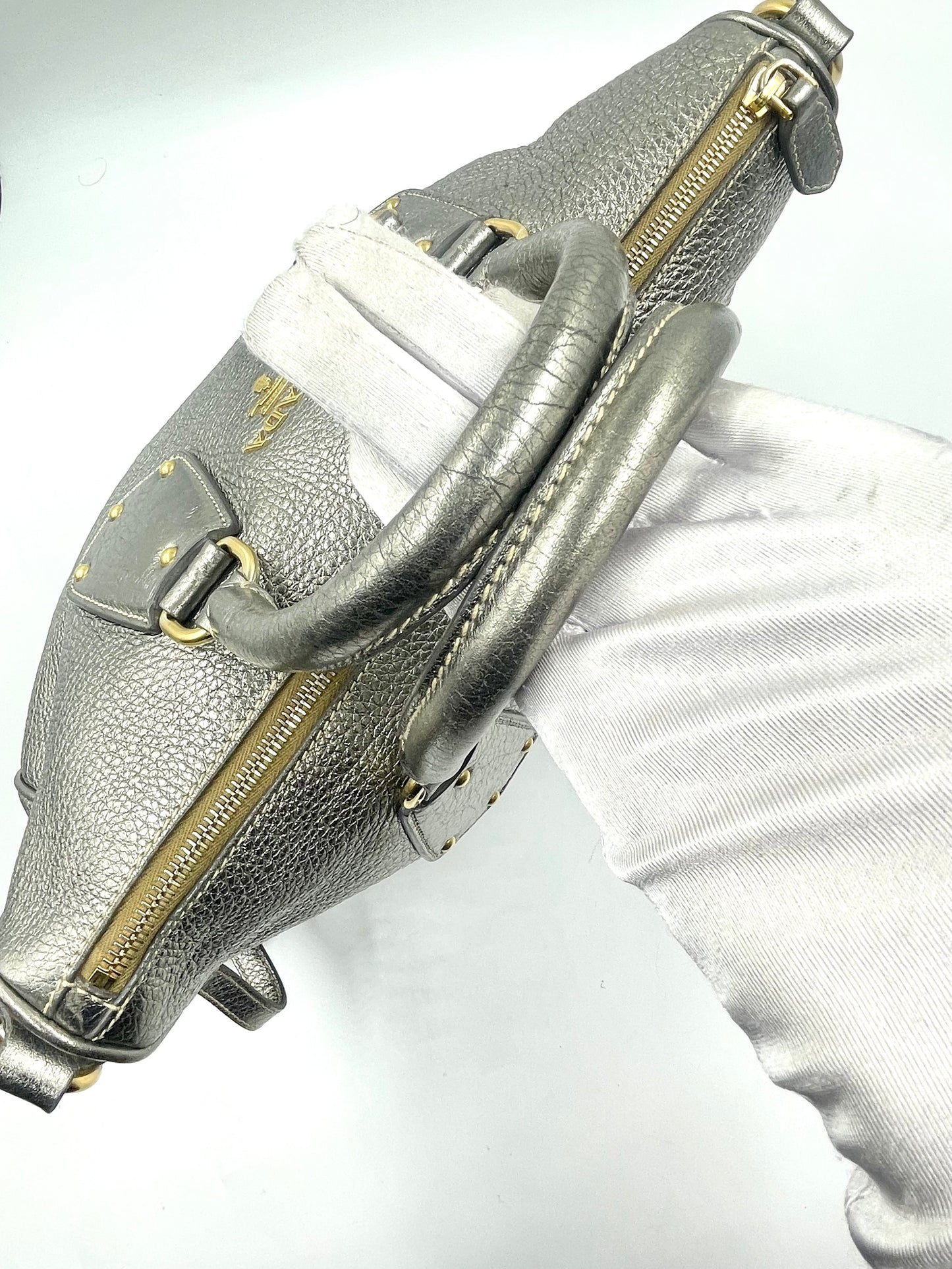 Prada Silver Metallic Vitello Daino Tote with rolled handles, gold hardware, and logo.