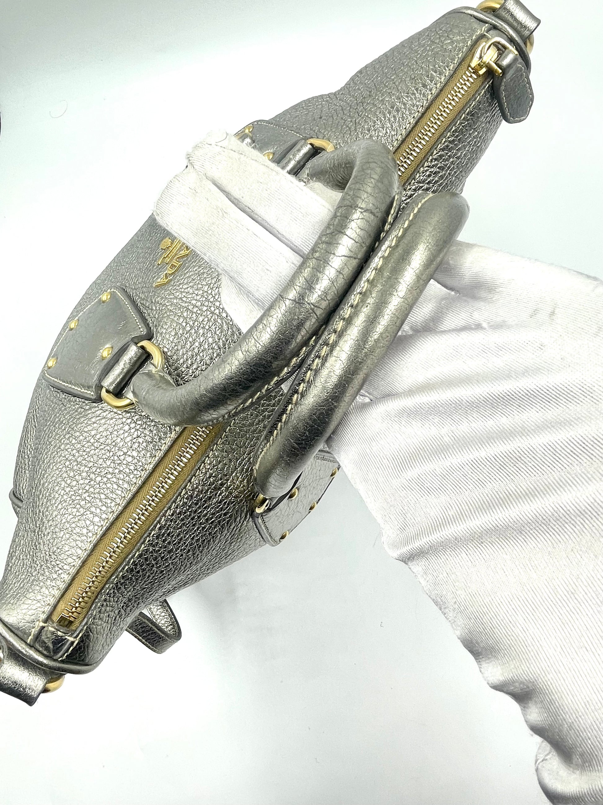 Prada Silver Metallic Vitello Daino Tote with rolled handles, gold hardware, and logo.