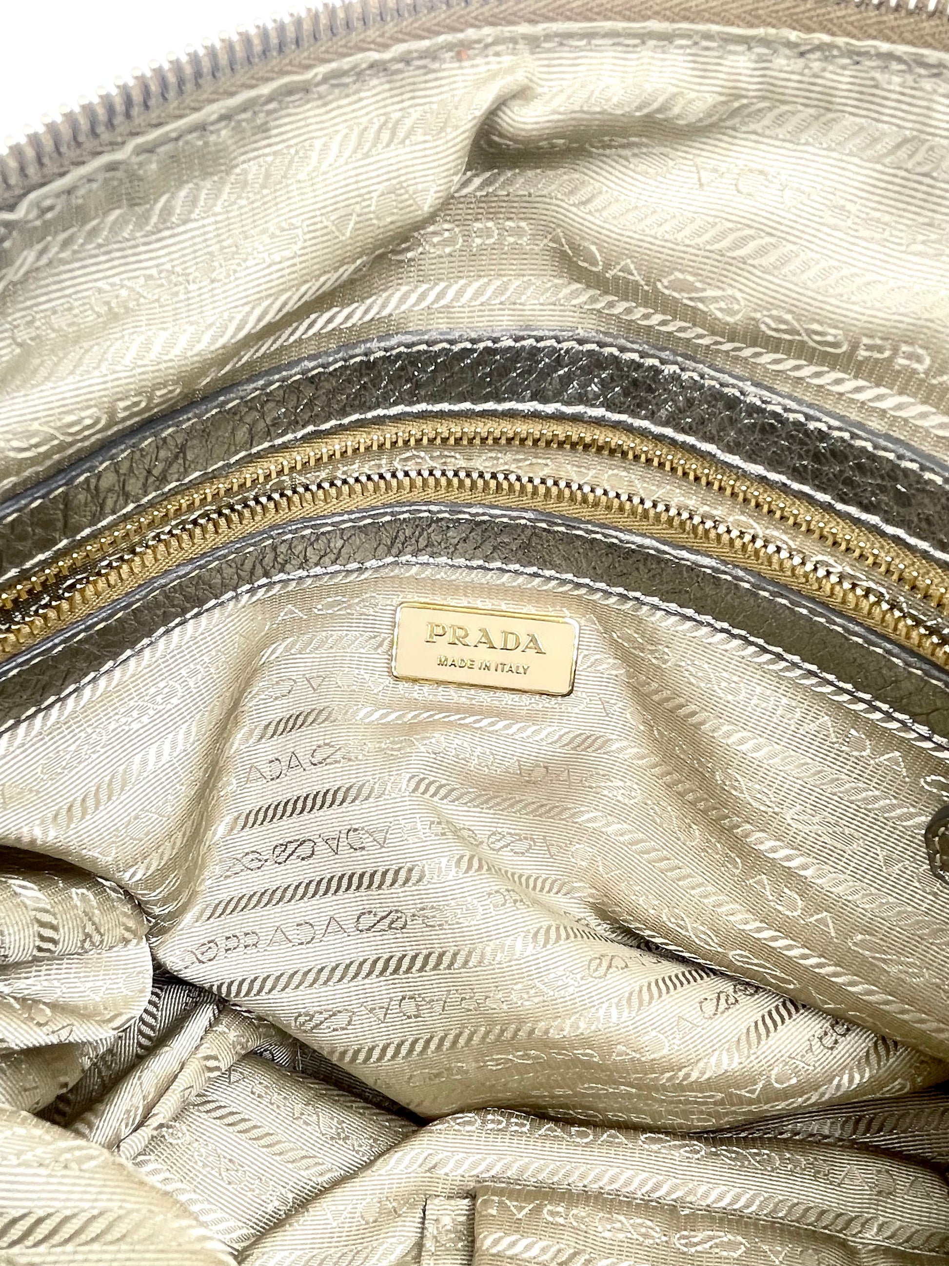 Prada Silver Metallic Vitello Daino Tote interior with gold-tone hardware, zip pocket, and logo plaque.