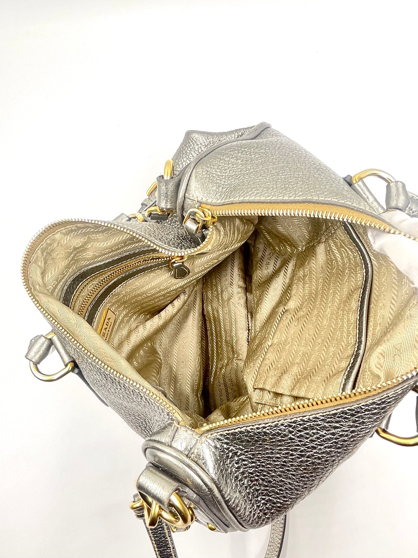 Prada Silver Metallic Vitello Daino Tote, open to show textile-lined interior with pockets and gold-tone hardware.