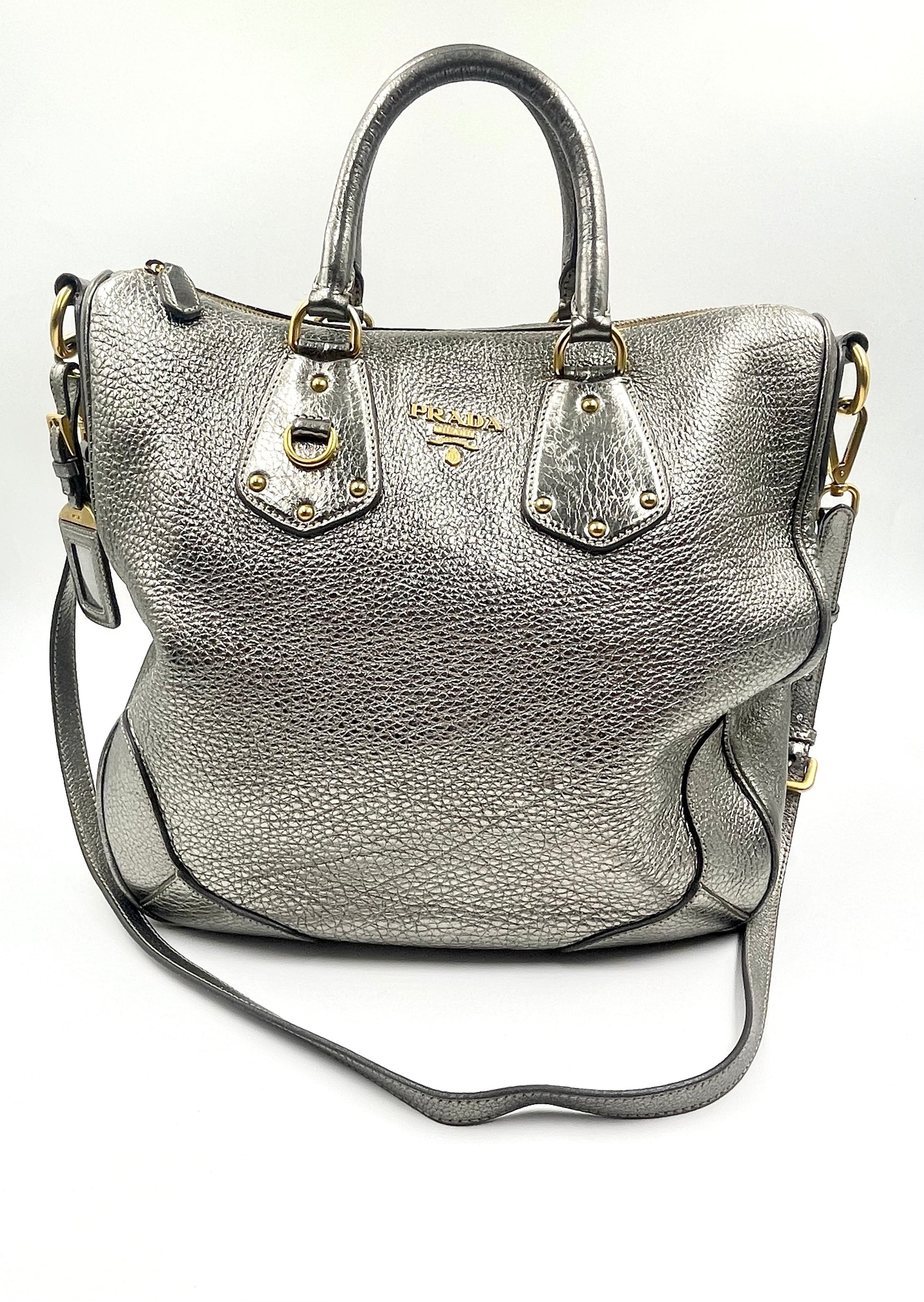 Prada Silver Metallic Vitello Daino Tote with rolled handles, gold hardware, and front logo.