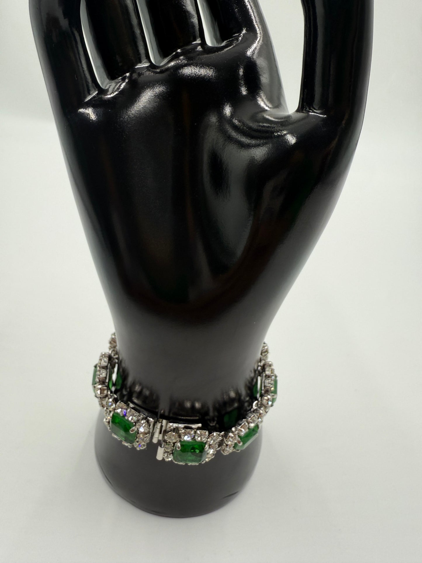 Rare 1972 Christian Dior emerald green glass stone bracelet with clear crystal rhinestones on a black display hand.