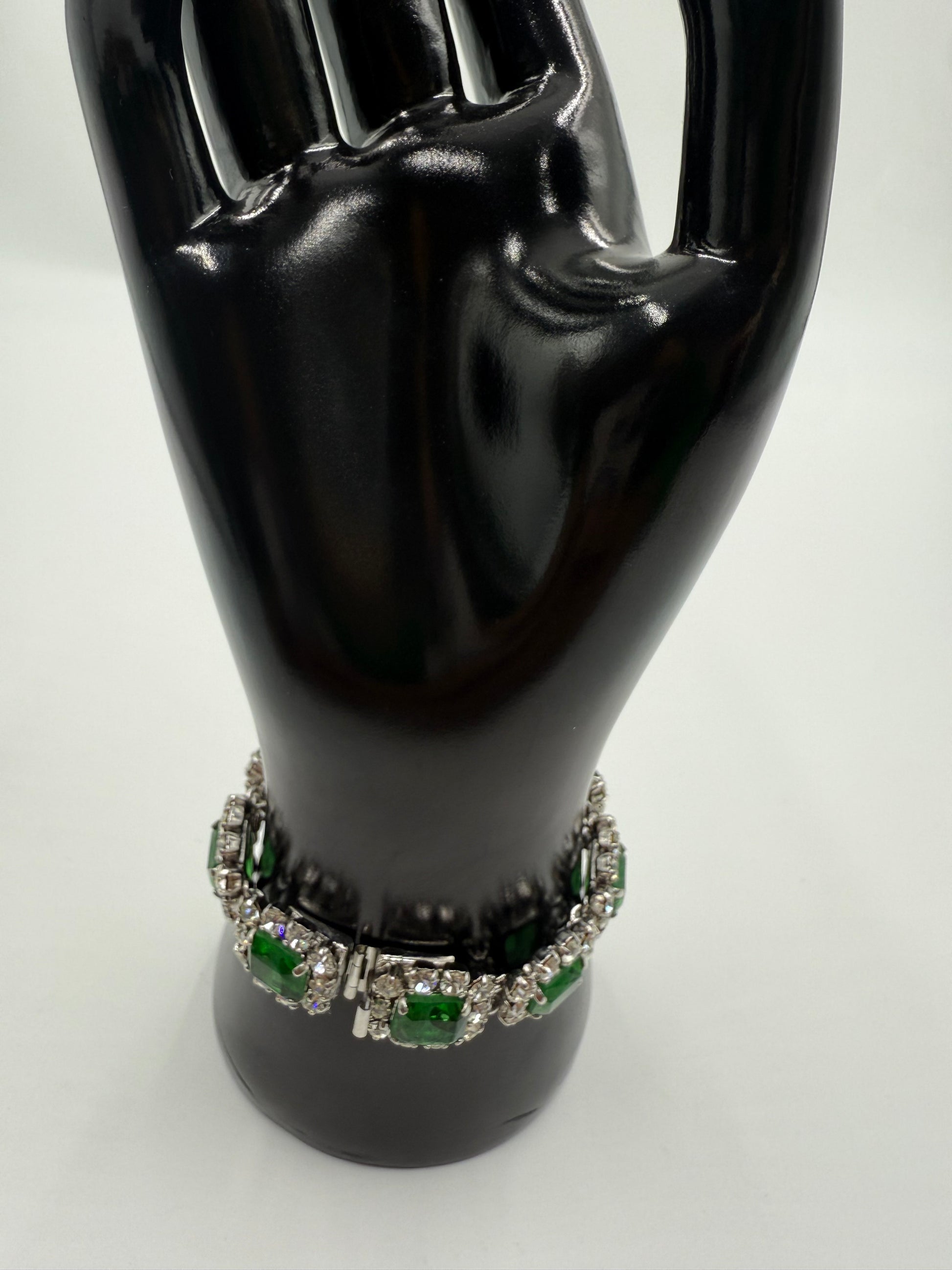 Rare 1972 Christian Dior emerald green glass stone bracelet with clear crystal rhinestones on a black display hand.