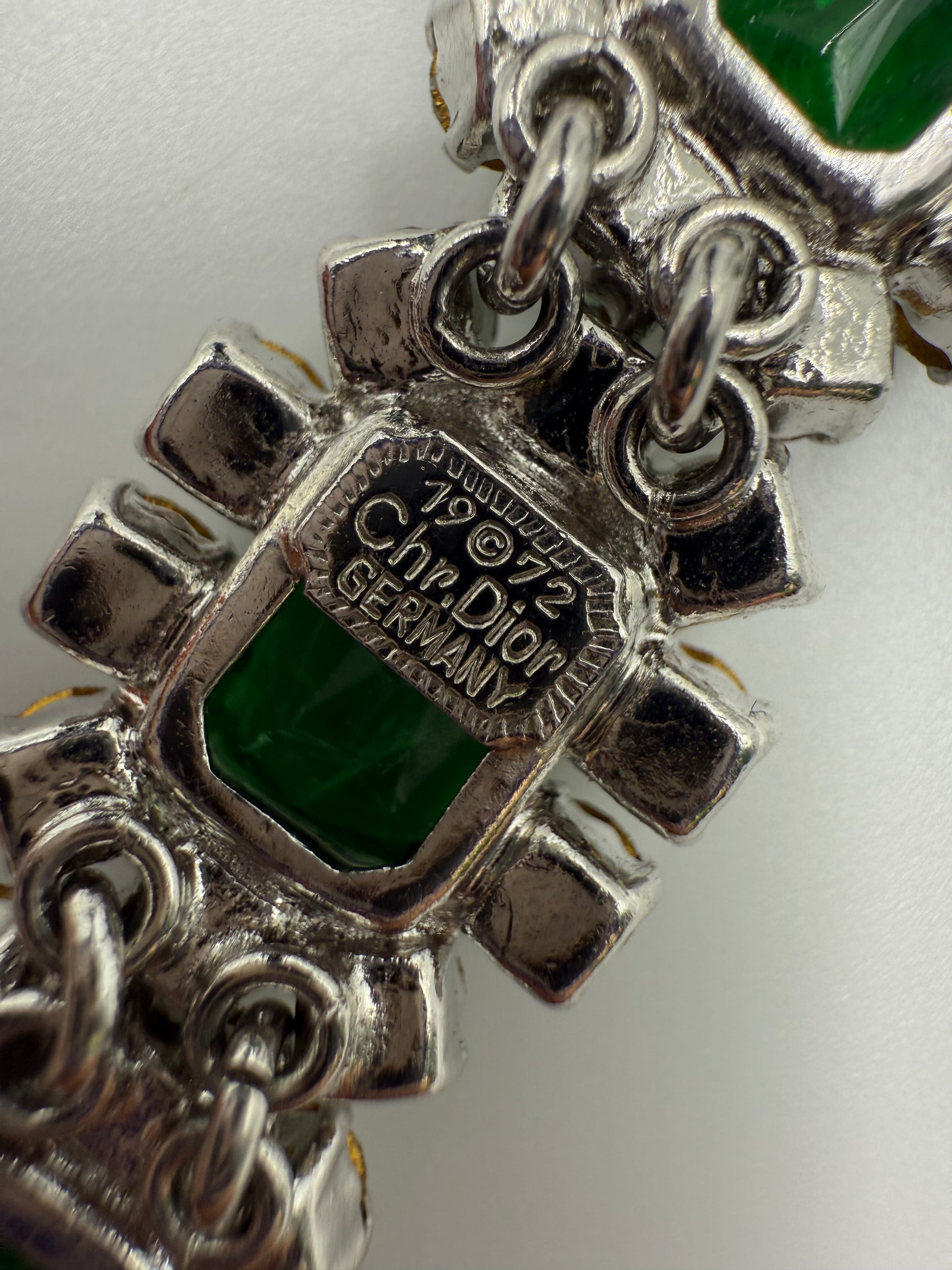 Close-up of the 1972 Christian Dior Germany signature on a silver-tone emerald green glass stone bracelet.