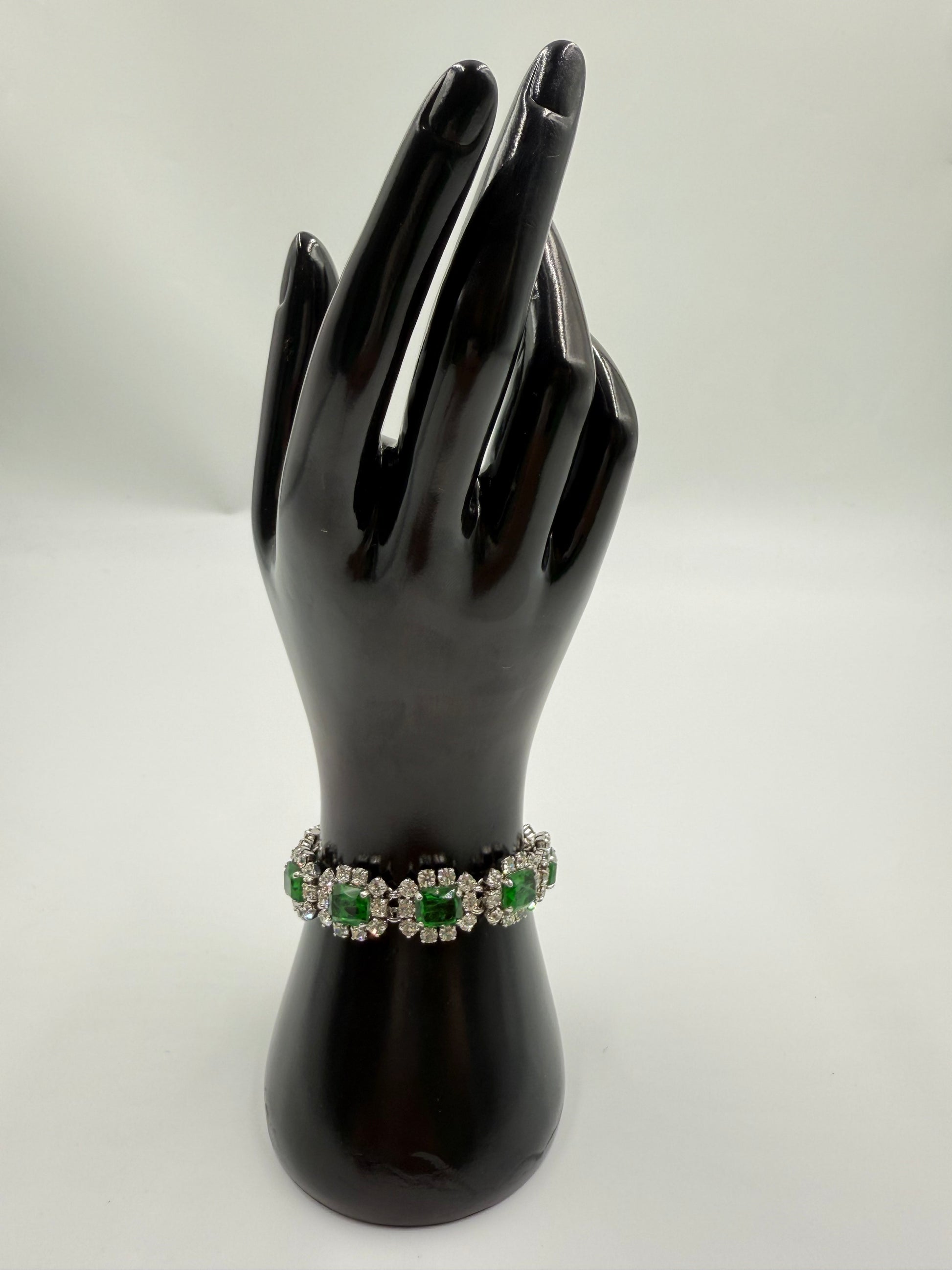 Rare 1972 Christian Dior emerald green glass stone bracelet with clear crystal rhinestones on a black display hand.