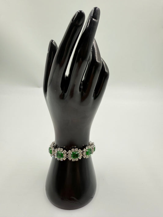 Rare 1972 Christian Dior emerald green glass stone bracelet with clear crystal rhinestones on a black display hand.