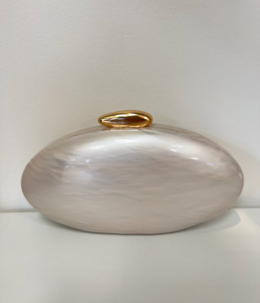 Oval resin clutch in pearlescent cream with a smooth, glossy finish and a polished gold pebble-shaped clasp.