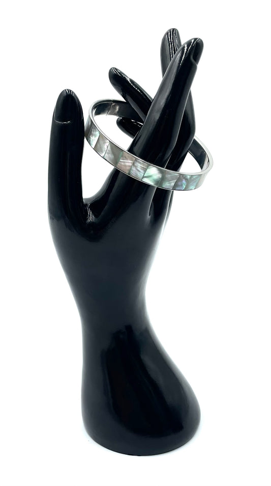 Silver bangle bracelet featuring iridescent abalone shell inlay on a black display hand.