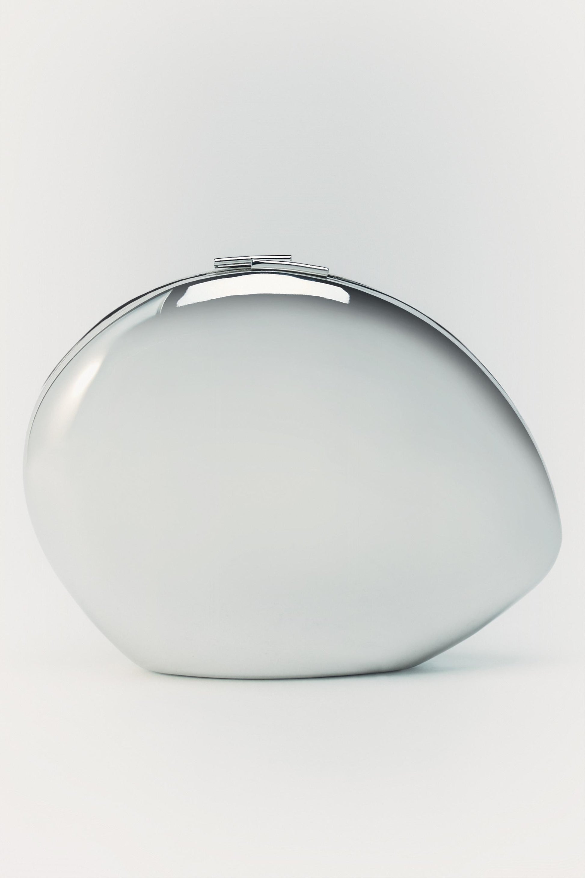 Sleek, oblong silver metal hard-shell clutch with a polished reflective finish and a minimalist top clasp closure.