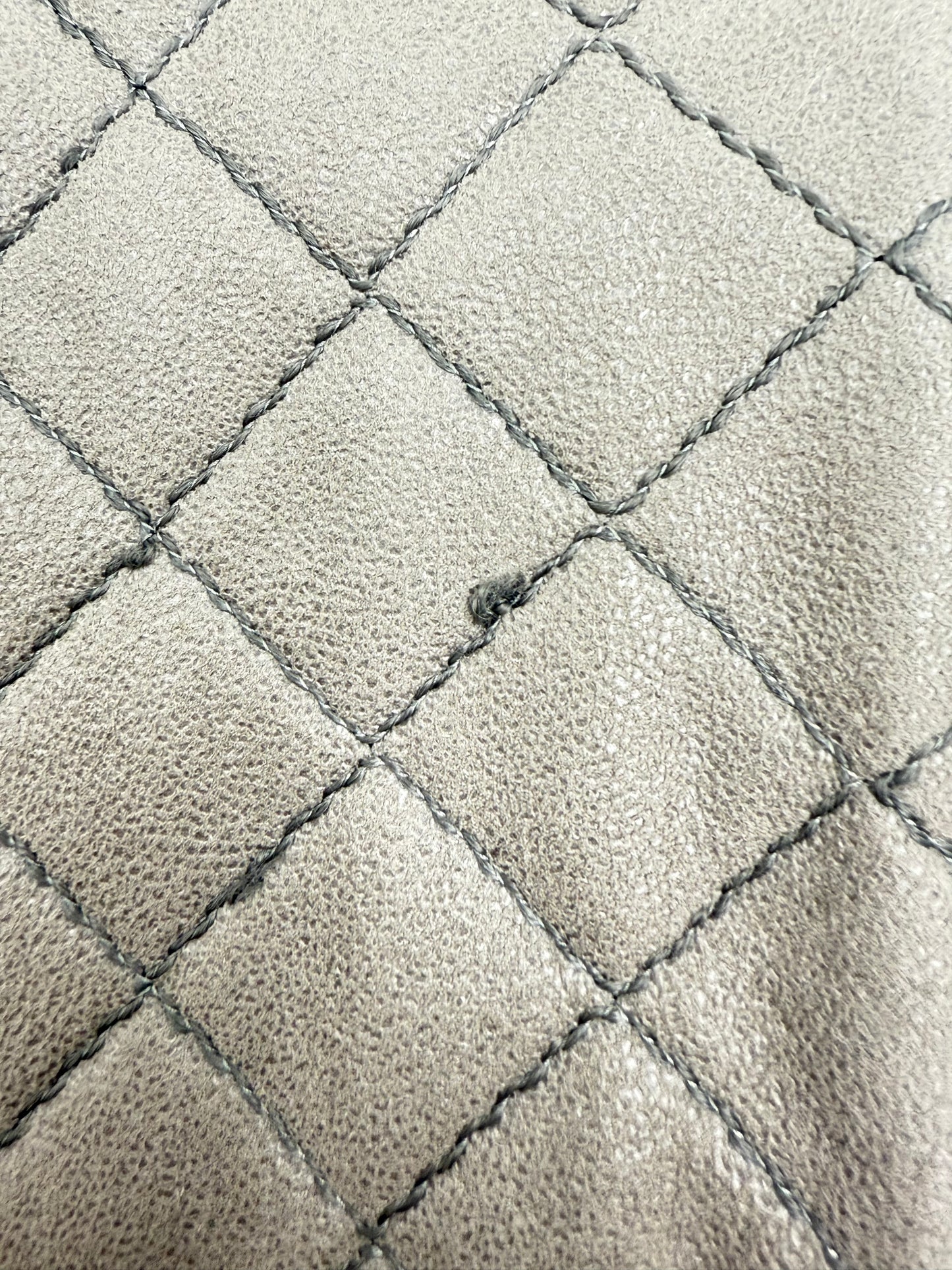 Close-up of Stella McCartney Falabella grey quilted suede bag with minor stitch flaw.
