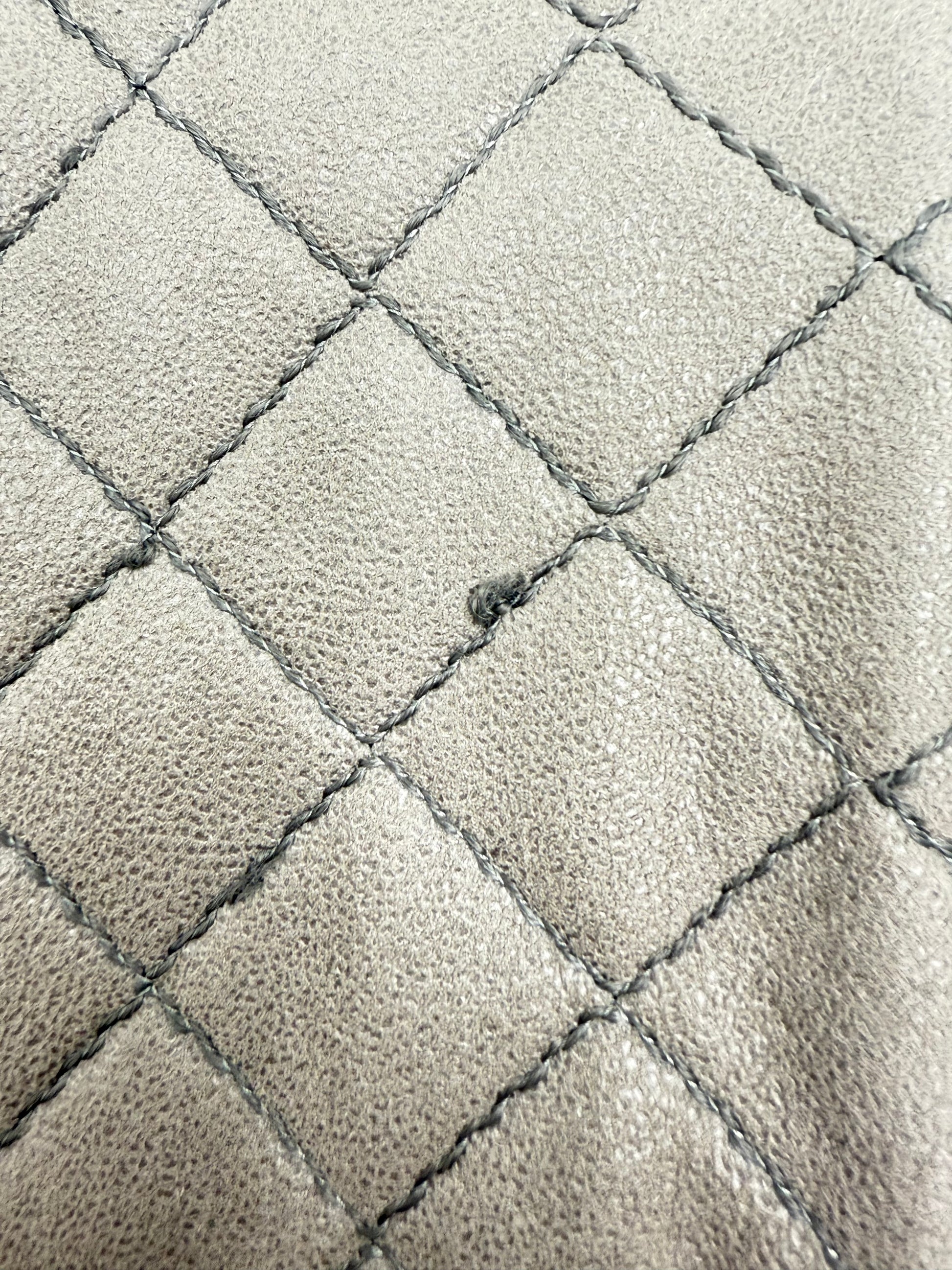 Close-up of Stella McCartney Falabella grey quilted suede bag with minor stitch flaw.