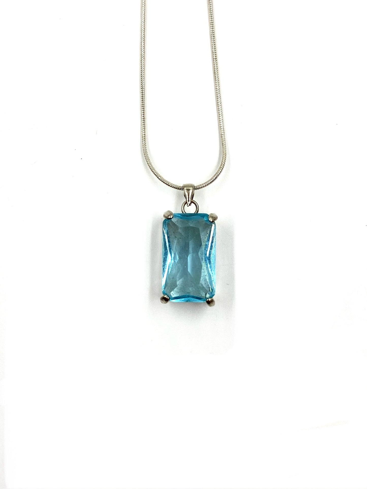 Sterling silver necklace with a rectangular blue topaz pendant on a white background.