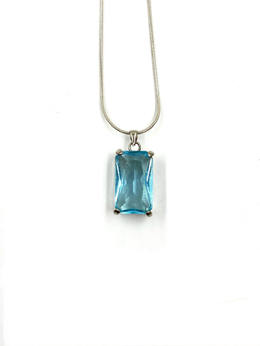 Sterling silver necklace with a rectangular blue topaz pendant on a white background.