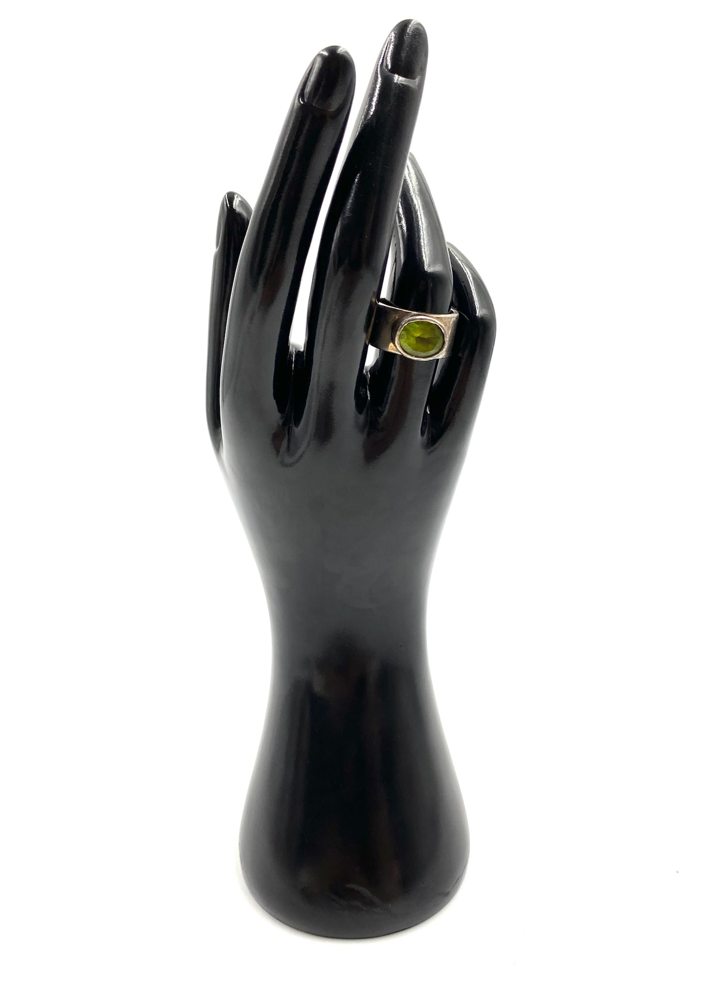Sterling silver ring with an oval peridot gemstone on a black display hand.