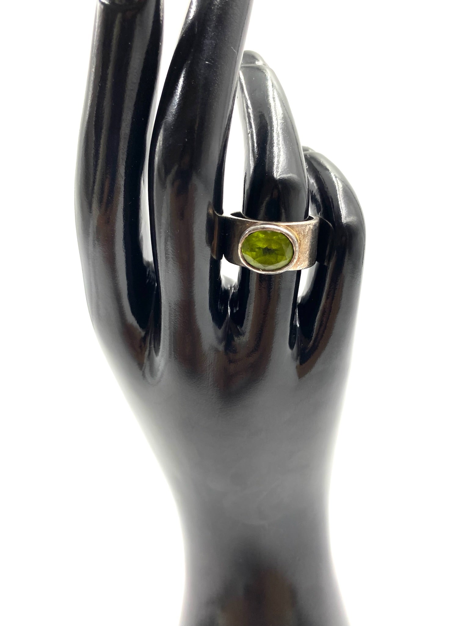 Sterling silver ring with an oval peridot gemstone, displayed on a black mannequin hand.