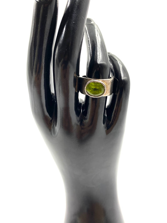 Sterling silver ring with an oval peridot gemstone, displayed on a black mannequin hand.