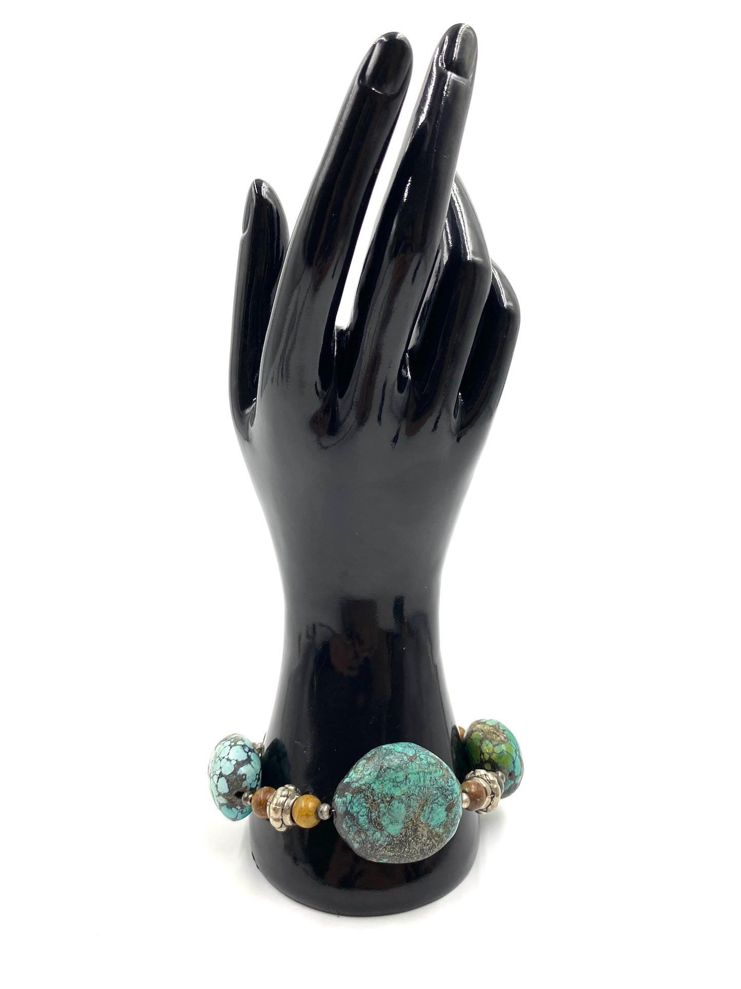 Turquoise stone bracelet with sterling silver toggle closure displayed on a black hand model.