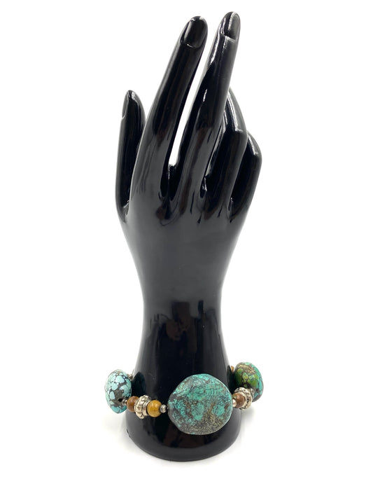 Turquoise stone bracelet with sterling silver toggle closure displayed on a black hand model.
