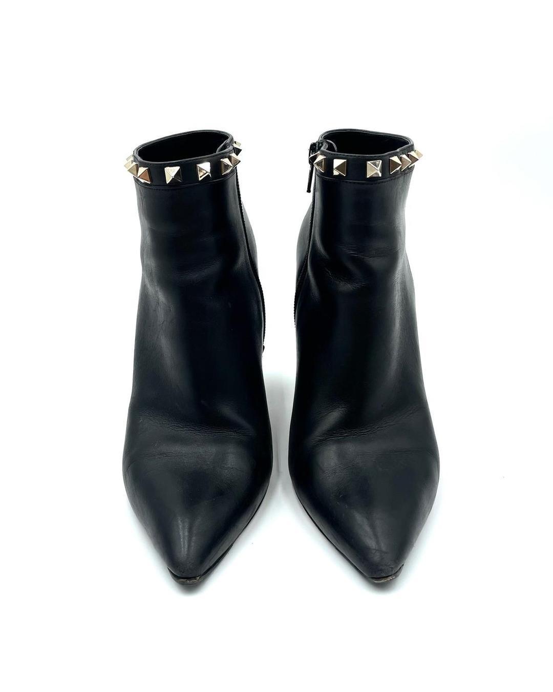 Valentino Garavani black leather pointed-toe ankle booties with gold stud trim and block heels.