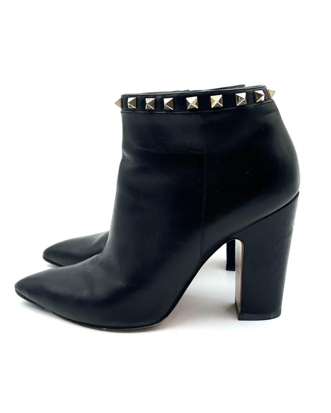 Valentino Garavani black leather pointed-toe ankle booties with gold Rockstud trim and block heels.