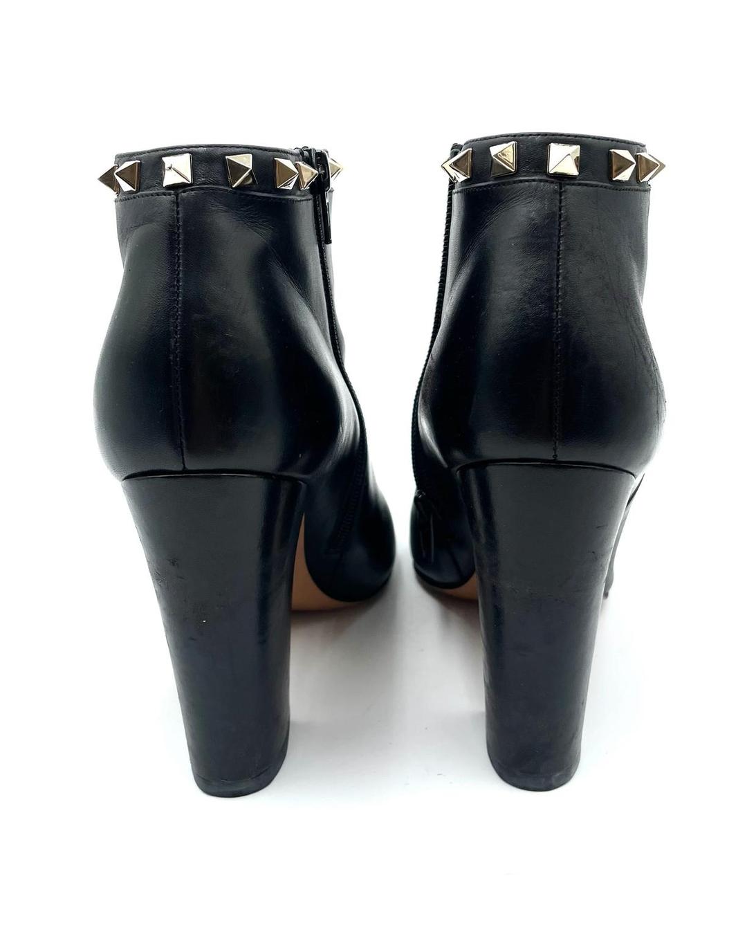 Valentino Garavani black leather ankle booties with gold Rockstud trim and high block heels.