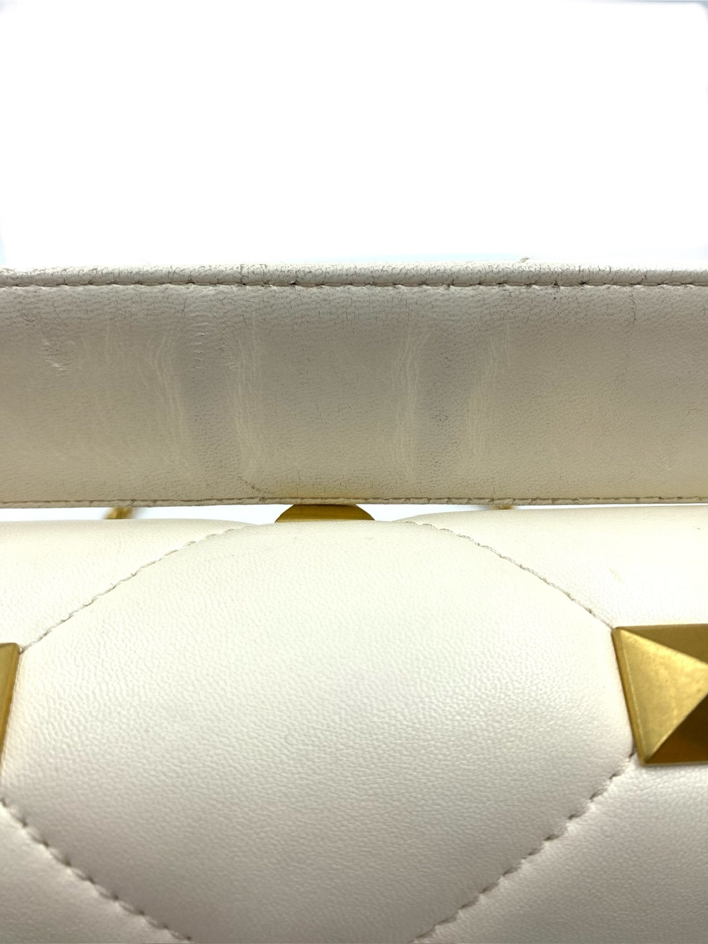 Close-up of Valentino Garavani White Medium Roman Stud Bag with wear on strap and quilted leather.