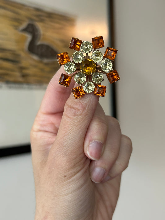 Vintage 1950s amber, citrine & topaz rhinestone brooch on gold-toned metal, held in hand.