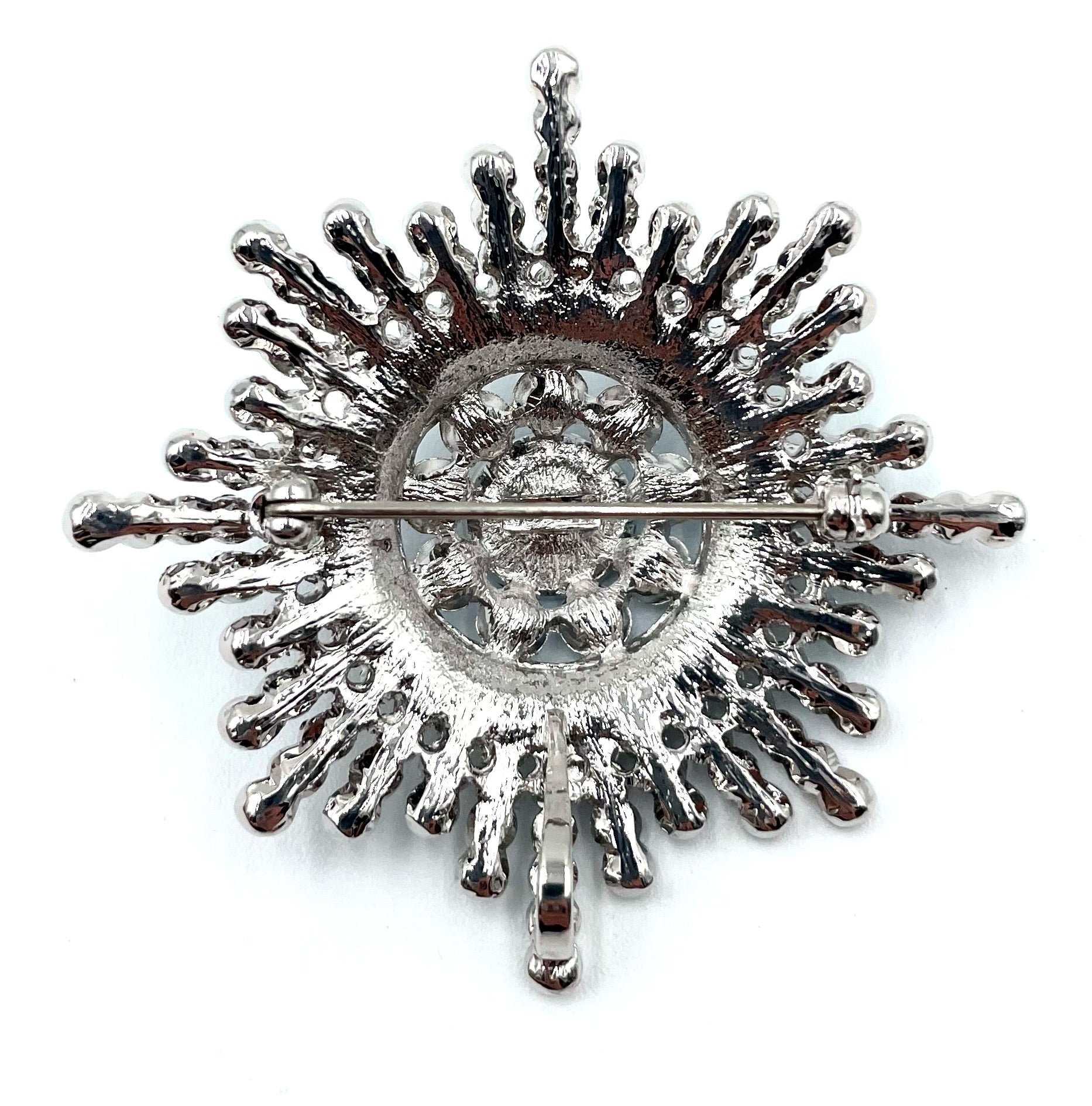 Back of a vintage silver-tone Butler sunburst brooch with a pin clasp.