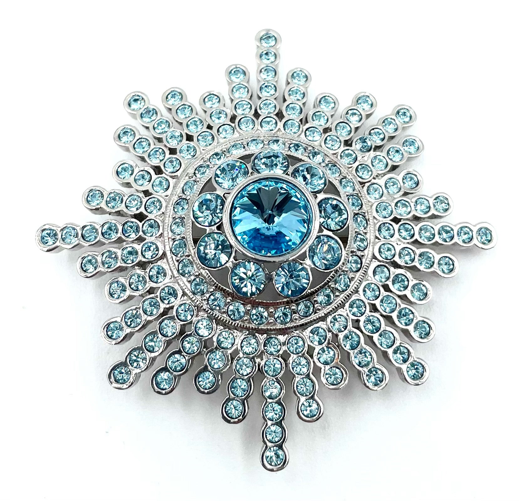 Vintage Butler blue crystal sunburst brooch with sparkling round stones and a large central blue gem.