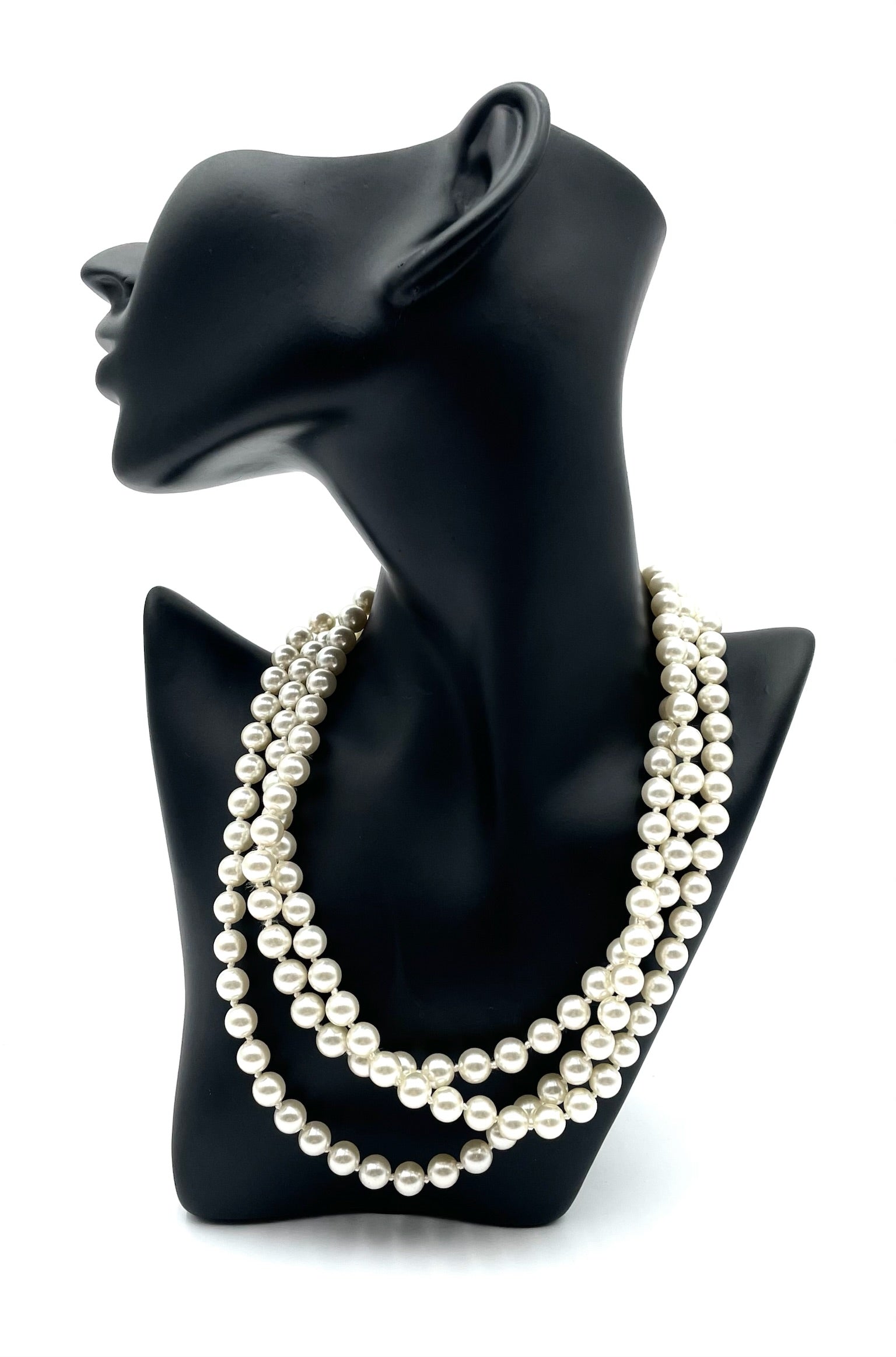 Vintage faux pearl choker necklace with three strands and a gold clasp on a black mannequin.