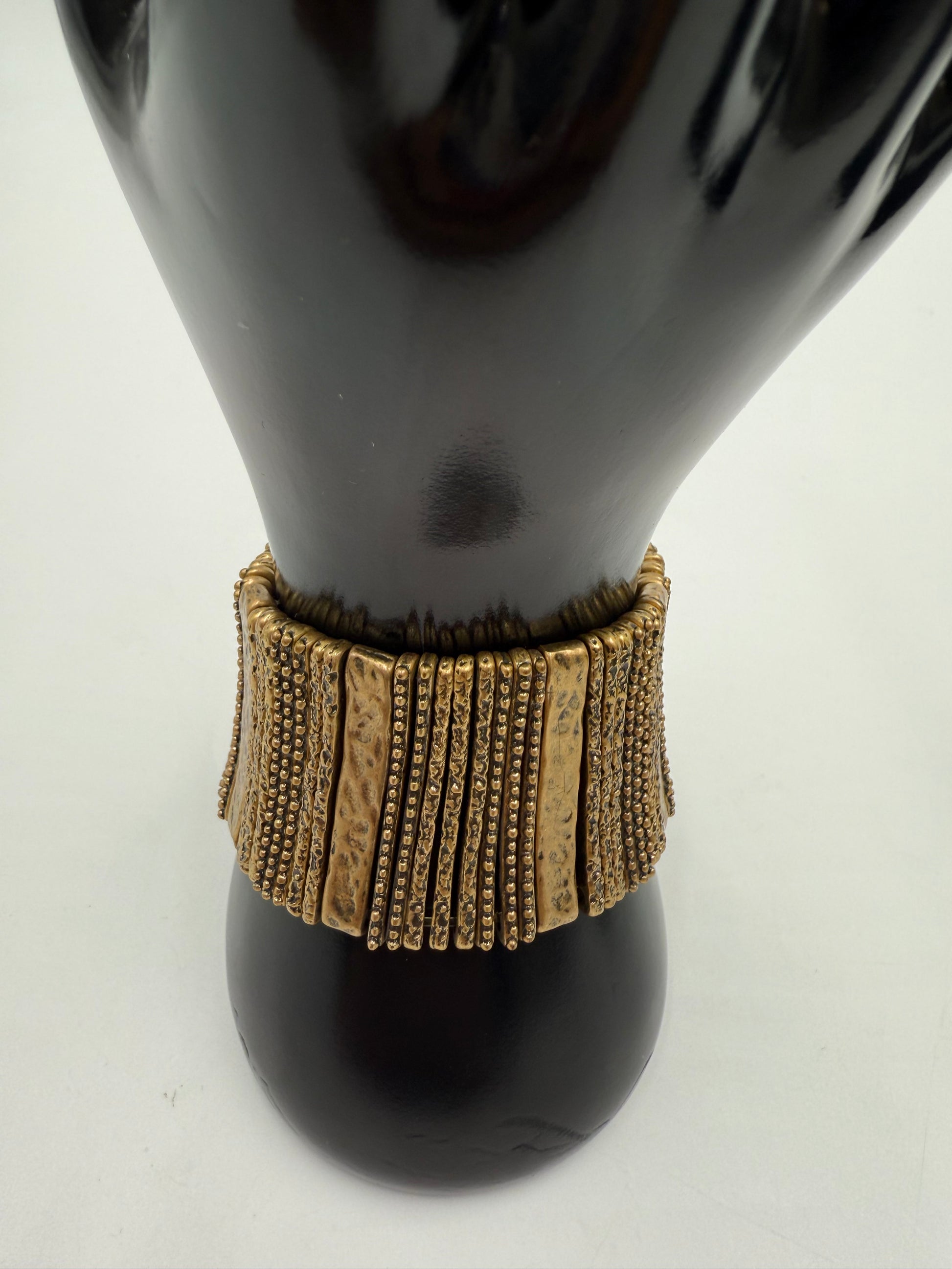 Vintage gold-tone costume jewelry stretch bracelet with textured and beaded segments on a black mannequin hand.