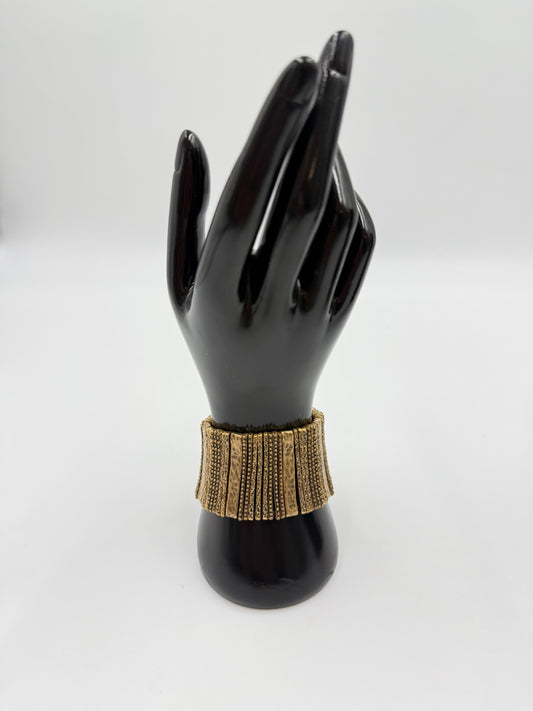 Vintage gold-tone costume jewelry stretch bracelet with textured rectangular links on a black mannequin hand.