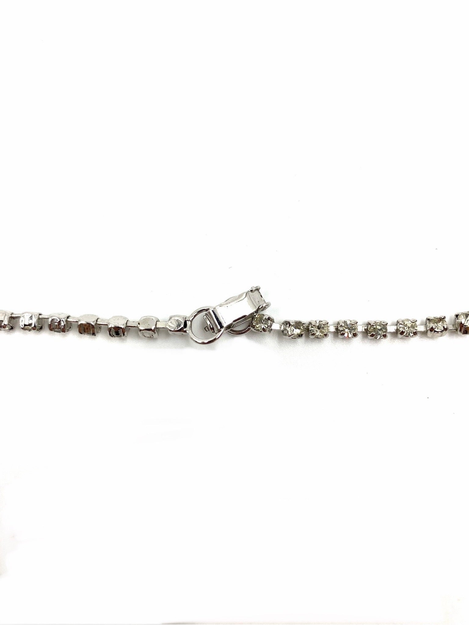 Close-up of a silver-tone vintage rhinestone necklace clasp and chain.
