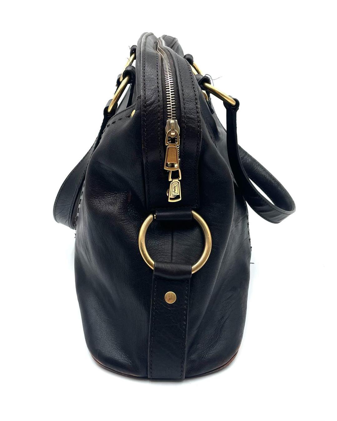 Side view of a dark brown leather Yves Saint Laurent Muse bag with gold-tone hardware, shoulder straps, and zip closure.